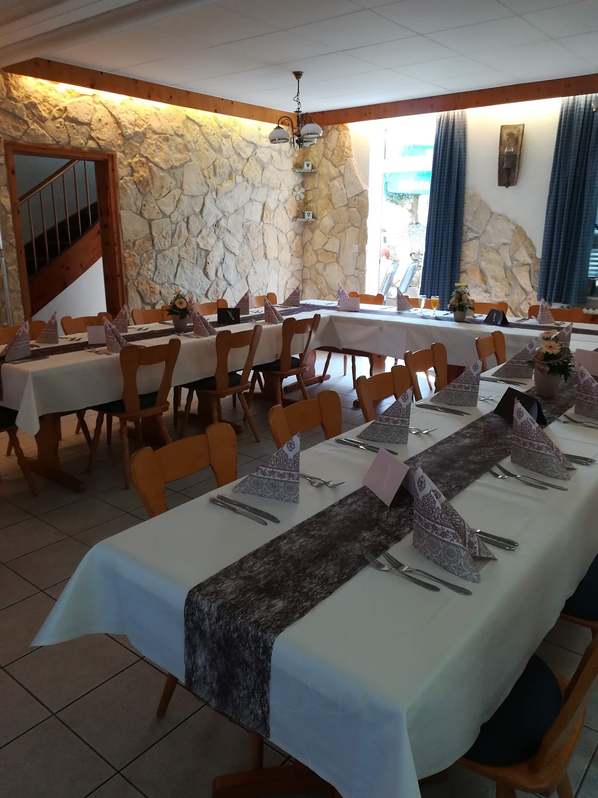 Die Gaststube im Gasthof Unot mit eingedeckten Tischen und Natursteinwand